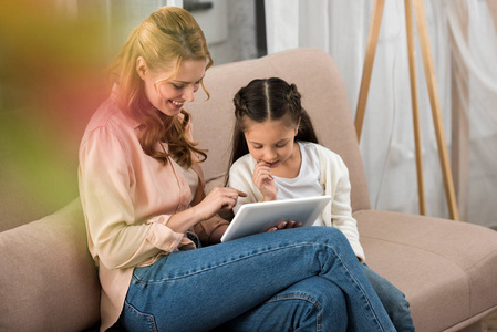 幸福的母亲和女儿一起使用数字平板电脑在家里