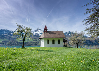 小白色教堂在一个美妙的山风景在春天与一个绿松石湖后面