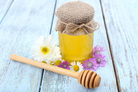 罐子，里面装满新鲜美味的蜂蜜和木制的桌子上的野花