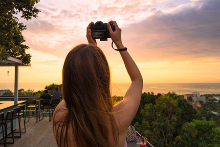 女孩与照相机拍摄美丽的日落图片