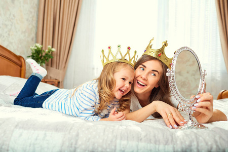 头上戴着皇冠的母亲和女儿正在 b 上玩耍。