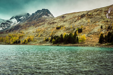 山湖与反射在岩石的镜子表面在多云阴雨天气。山地与自然之美