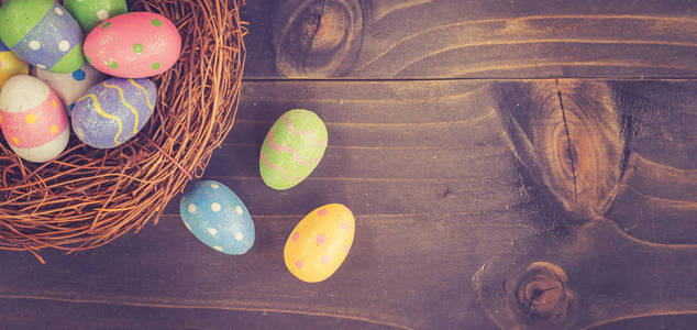 五颜六色的复活节彩蛋和巢在木背景与空间