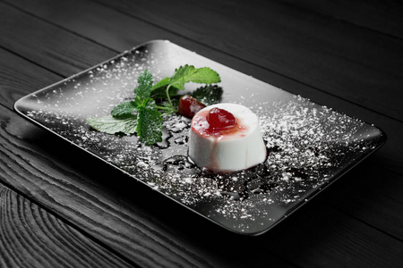 黑木背景下的草莓糖浆和薄荷叶意大利智世陶的甜点照片
