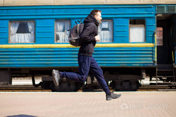 一个带着大包的年轻人在火车站跑.乘火车旅行