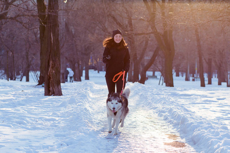 年轻女子亚军训练在冬季公园与沙哑的狗
