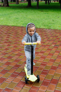 湿透在雨中, 一个男孩穿着运动西装溜冰鞋。春季漫步在城市公园, 阴雨天气