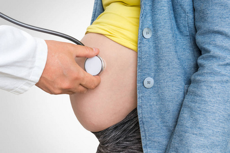 儿科医生用听诊器听心跳婴儿怀孕妇女怀孕的概念