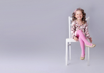 性格开朗的小女孩坐在椅子上用微笑