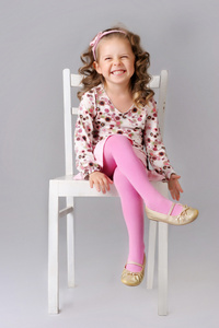 可爱的小女孩坐在椅子上，微笑