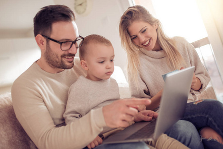 快乐的年轻家庭看卡通在笔记本电脑一起