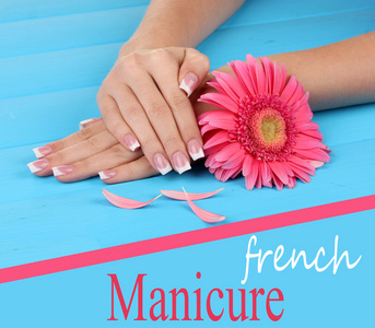 女人手与法国修指甲和花在蓝色木制背景