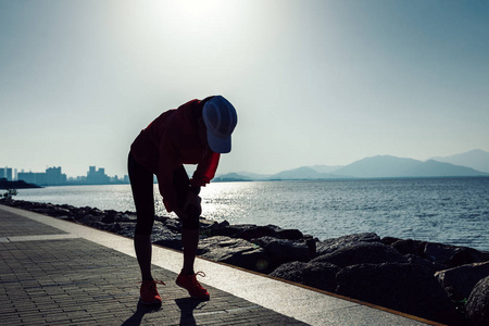 妇女赛跑者举行运动受伤的膝盖在日出海滨