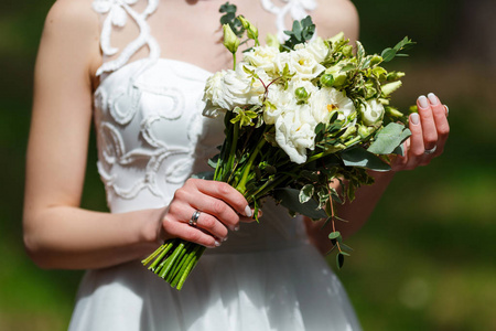 优雅的新娘在白色婚纱礼服与花边握在手
