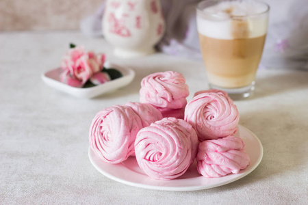 美丽可口的甜点。粉红色的西风在白色的盘子和粉红色的花朵。浅灰色背景下的浆果西风