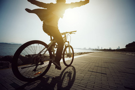 在日出海岸骑自行车的快乐骑车的剪影
