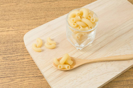 食物和菜 生的肘通心粉或 Gomiti Pasta 在玻璃杯子和木勺子在砧板上