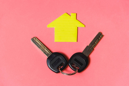 在粉红色背景上有两个银色钥匙的房子的象征。Copyspace 的简约主义概念