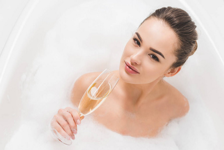 美丽的妇女与玻璃的香槟洗澡