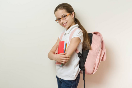 一个微笑的女学生10岁的肖像与眼镜, 与背包, 笔记本
