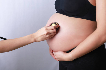 医生使用手和听诊器年轻怀孕妇女