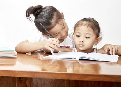 两个小女孩泰国家庭作业在柚木桌。设计空间