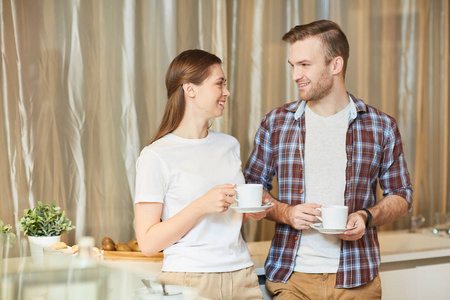 年轻的丈夫和妻子在厨房里喝咖啡, 早上说话