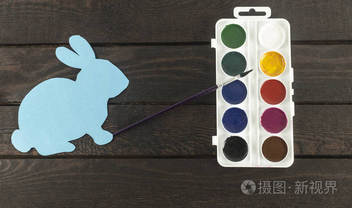 卡兔与画笔在它的手和一套水彩颜料