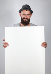 白色背景上孤立的年轻男子拿着一片空白，戴着帽子的肖像