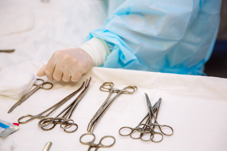 手术时在诊所的医疗桌上做手术器械的特写。金属无菌剪刀夹子手术针在桌上或医生手上。健康的概念, 工具