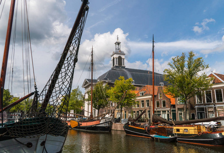 传统的木制帆船在水道中。教会在背景。荷兰斯希丹历史悠久的海港