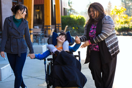 残疾男孩在轮椅牵手与照顾者步行