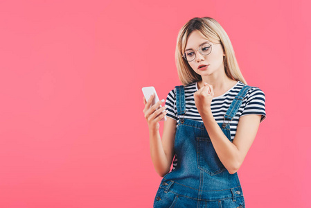 年轻女子的肖像显示拳头的智能手机隔离粉红色