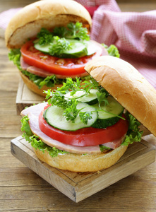 新鲜的蔬菜和火腿片放在一块木板的快餐汉堡