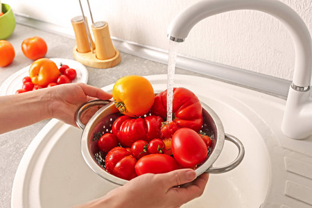 女手洗西红柿在漏勺在厨房