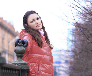 年轻妇女在红色秋天夹克在城市背景