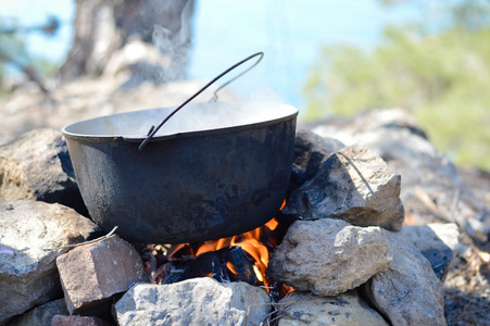 长柄锅悬在海岸旅游营地在岩石上的火