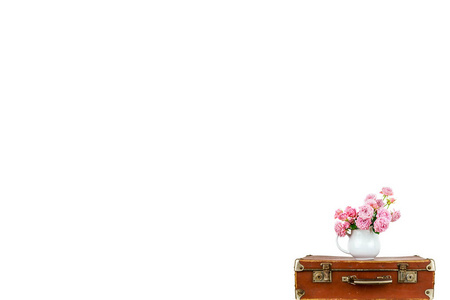 在壶上旧的棕色复古手提箱的粉红色花朵。罐子里的玫瑰。粉红玫瑰花束。破旧的别致。质朴的概念