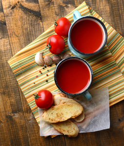 在颜色杯子 面包和新鲜的西红柿，木制的背景上自制的番茄汁