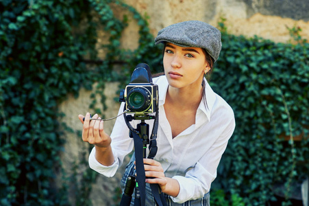城市街道上的女摄影师。时尚的女孩与旧相机