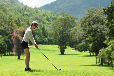 亚洲妇女打高尔夫球在一个美丽的自然高尔夫球场