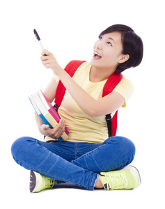 美丽的学生亚洲女孩握笔，坐在地板上