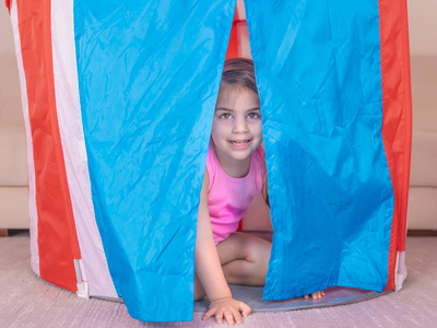 可爱女孩的肖像在一个五颜六色的玩具帐篷里玩耍。选择性聚焦与小景深