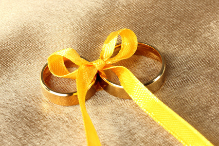 在明亮的背景上丝带绑的结婚戒指