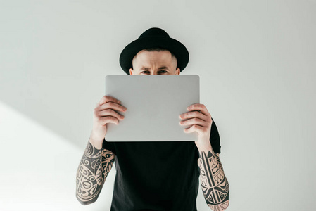 英俊的纹身男子看着从笔记本电脑白色