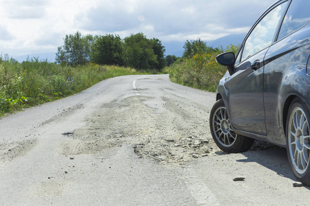 道路上有洞的汽车和裂缝沥青