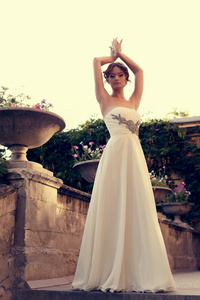 美丽的新娘在雅致的连衣裙在夏季公园摆姿势