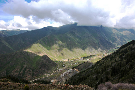 美丽的风景的绿色山丘陵蓝色多云的天空吉尔吉斯斯坦。高村庄和建筑