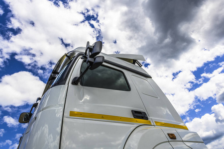 蓝天上的白色积云反映在一辆大型卡车的侧面窗户和后视镜上。