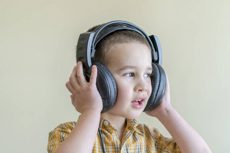 一个4岁的男孩在衬衫用心听音乐在大黑耳机